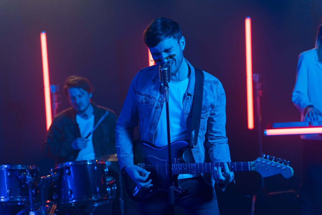 Offerings Vibrant band performing with neon lights, featuring electric guitar and drums.
